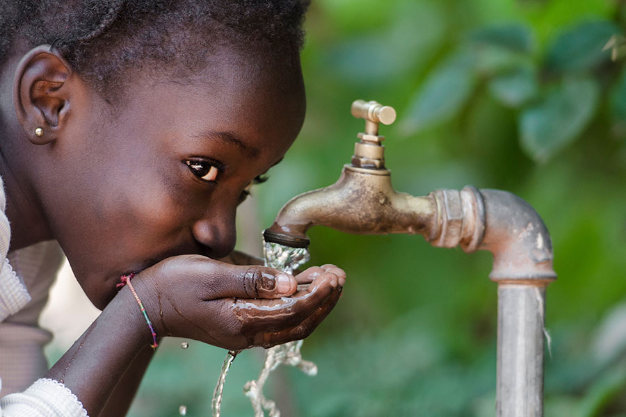 Kind trinkt Wasser aus Wasserhahn