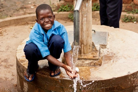 Ein Junge schöpft Wasser am Brunnen